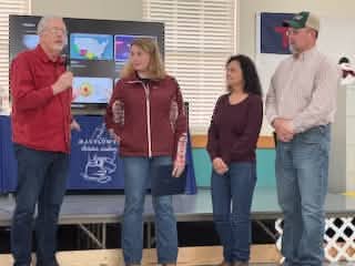 Four adult guest speakers presenting in front of a classroom display